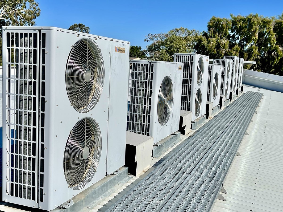 Row of commercial condenser units on a metal roof