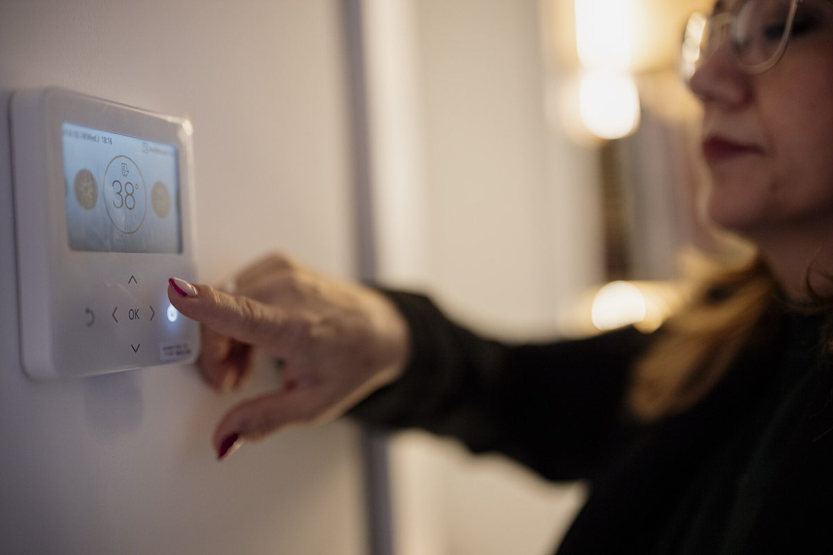 Person adjusting a digital wall thermostat